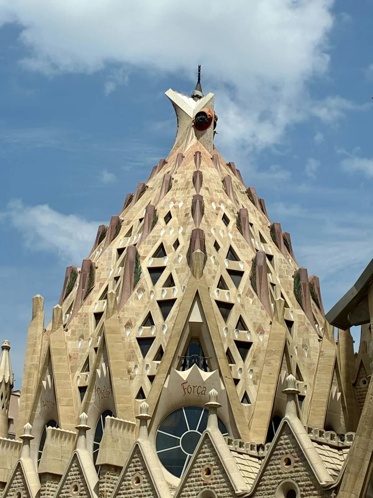 Parte superior de una torre de la Sagrada Família bajo un cielo nublado